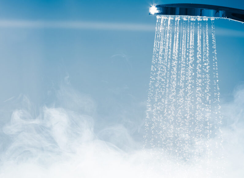 Hot water flowing from a showerhead in a steamy shower