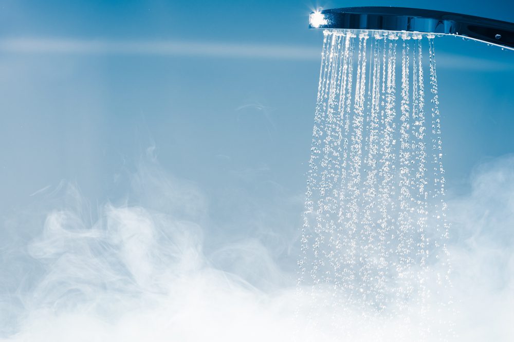 Hot water flowing from a showerhead in a steamy shower