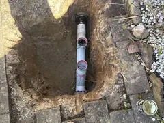 New PVC sewer pipe and junctions in a dig beside paving in Bangor